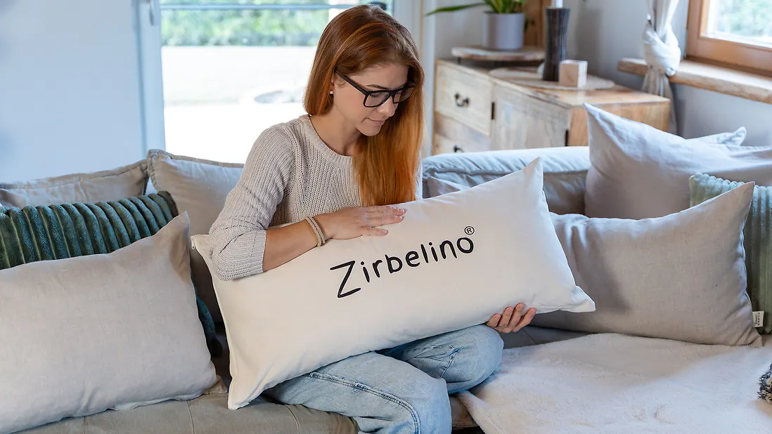 Frau auf Sofa mit ZIRBELINO Zirbenkissen aus Baumwolle 40x80 cm